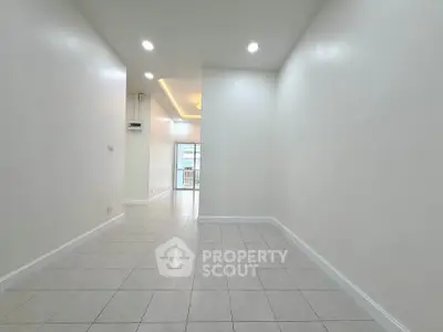 Spacious empty room with tiled flooring and bright lighting, ideal for customization.