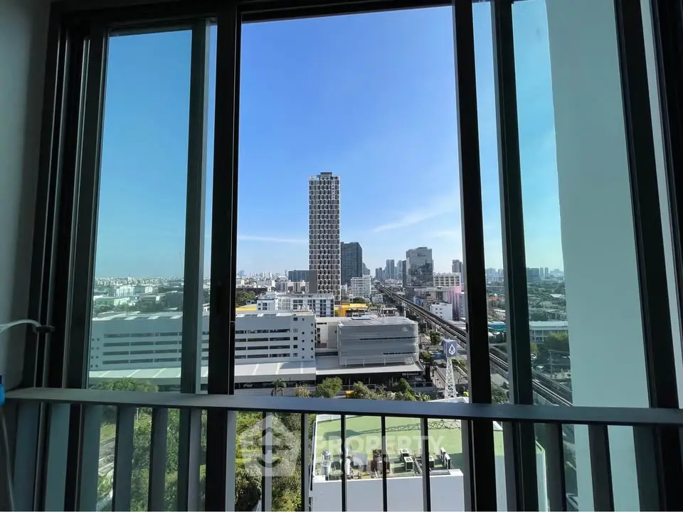 Stunning cityscape view from high-rise apartment balcony with clear blue sky.