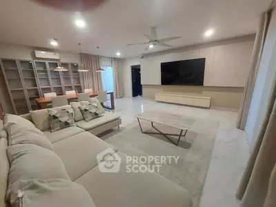 Spacious modern living room with elegant decor and large TV, perfect for relaxation and entertainment.