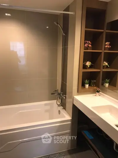 Modern bathroom with sleek bathtub and stylish shelving in contemporary apartment.