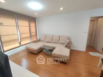 Spacious living room with modern beige sectional sofa and wooden flooring, perfect for relaxation.
