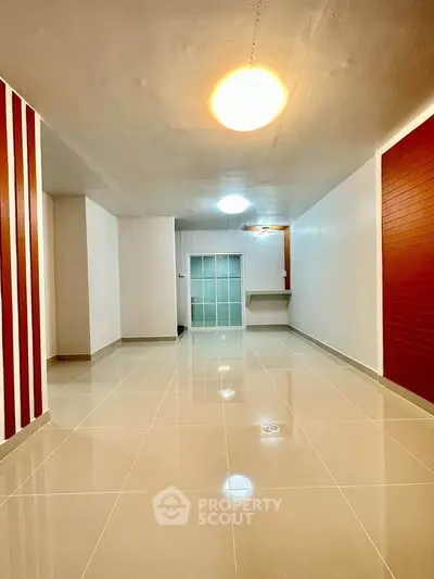 Spacious modern living room with glossy tiled floors and stylish accent walls.