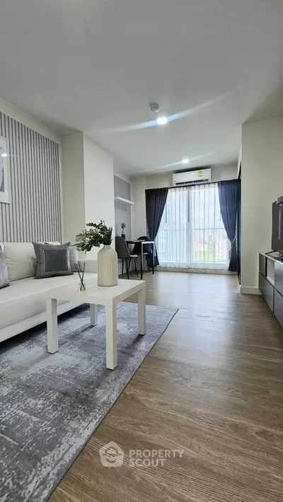 Modern living room with stylish decor and large window offering natural light.