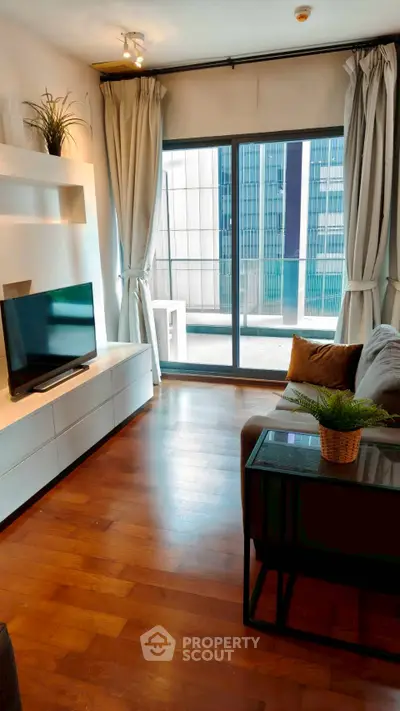 Modern living room with hardwood floors and large windows overlooking cityscape.