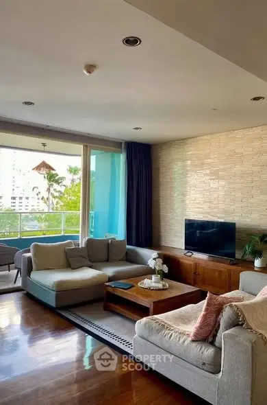 Spacious living room with modern decor and large windows opening to a balcony with a view.