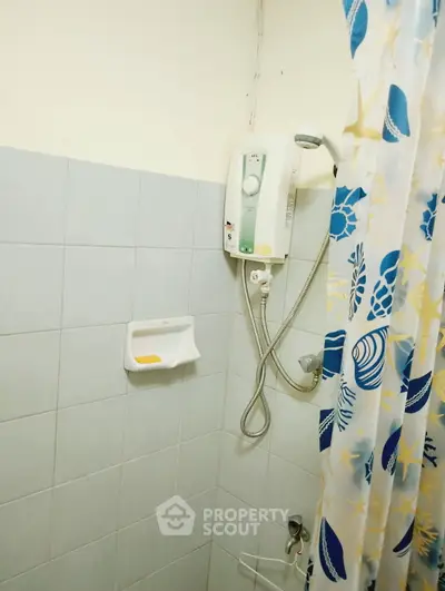 Compact bathroom with shower and decorative curtain in a cozy home setting.