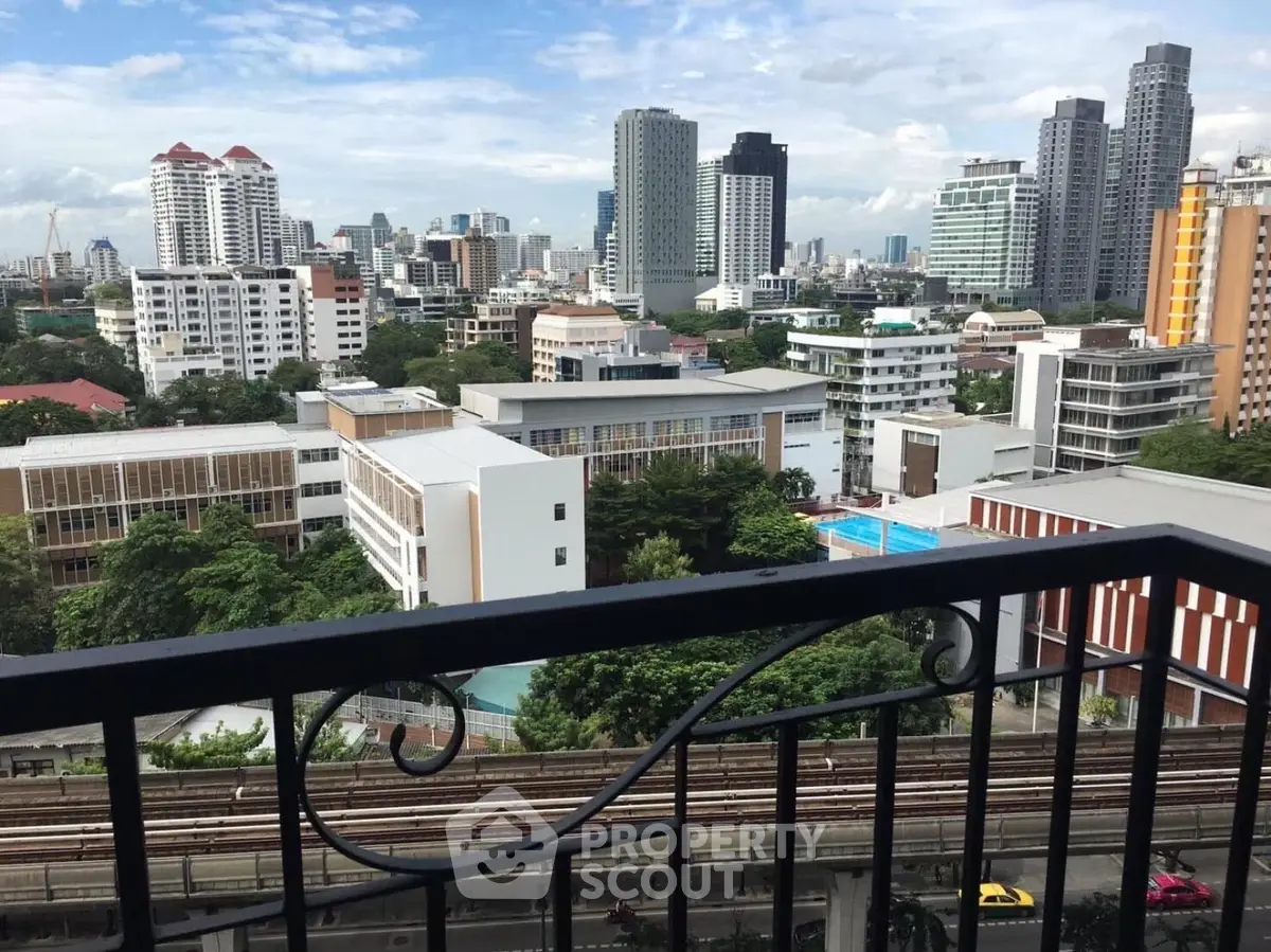 Stunning cityscape view from a high-rise balcony overlooking urban skyline and lush greenery.