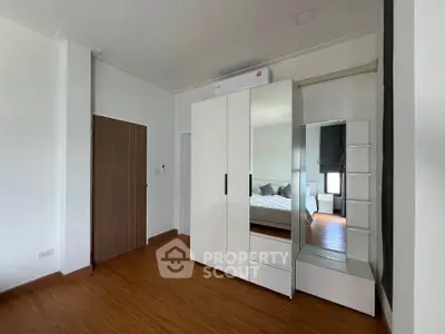 Spacious bedroom with modern wardrobe and wooden flooring, perfect for a cozy living experience.