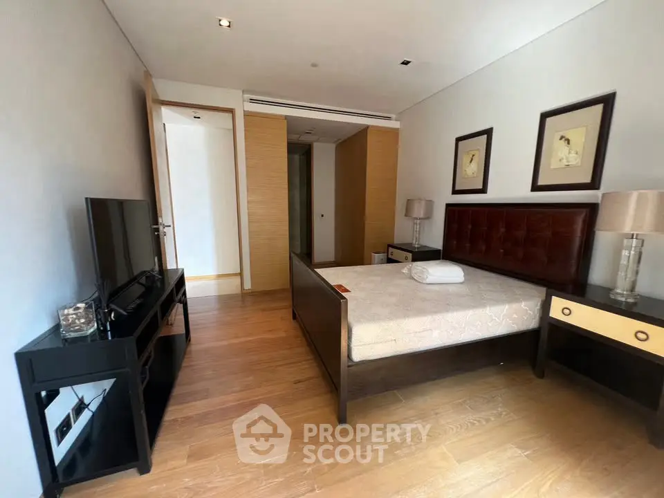 Spacious bedroom with modern furnishings and wooden flooring in a luxury apartment.