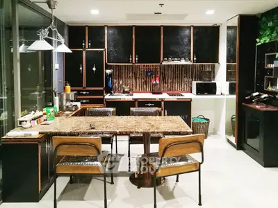 Modern kitchen with sleek black cabinets and marble dining table, featuring open layout and contemporary design.