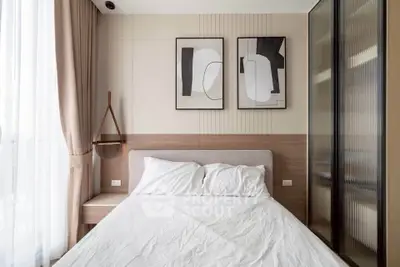 Modern bedroom with stylish decor and natural light, featuring abstract art and elegant furnishings.