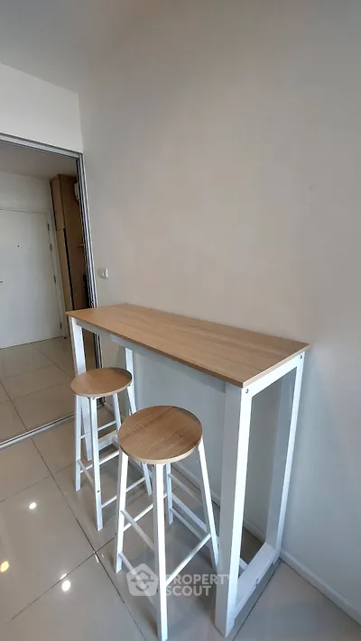 Modern minimalist kitchen with sleek bar table and stools, perfect for compact living spaces.