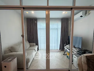 Modern living room with glass sliding doors, cozy sofa, and entertainment setup.