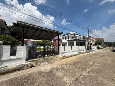 Modern two-story house with gated driveway and carport in suburban neighborhood.