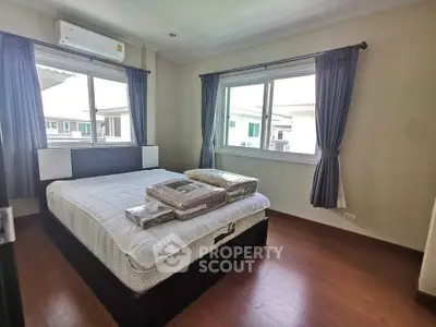 Spacious bedroom with large windows and modern furnishings in a well-lit home.