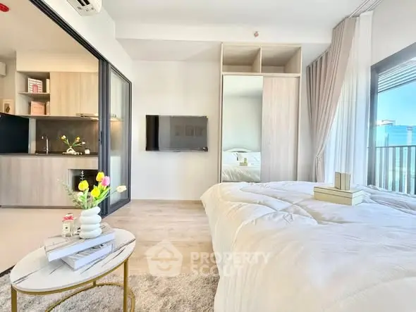Modern bedroom with cozy decor and city view, featuring a sleek TV and stylish furnishings.
