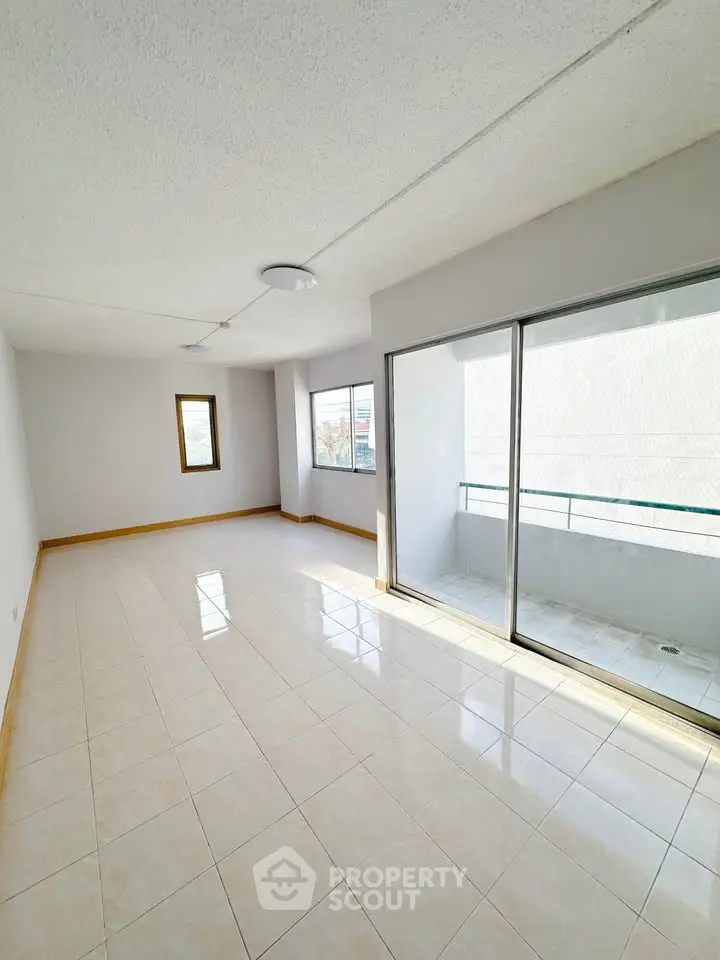Spacious sunlit living room with balcony access and large windows