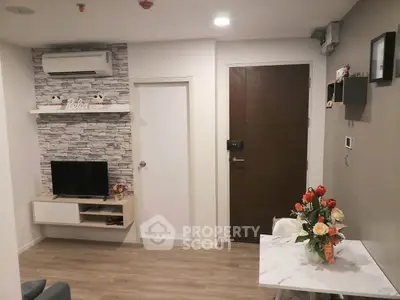 Modern living room with stylish decor and air conditioning, featuring a cozy TV area and elegant floral arrangement.