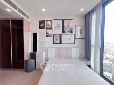 Modern bedroom with city view, stylish wall art, and sleek furniture in a high-rise apartment.