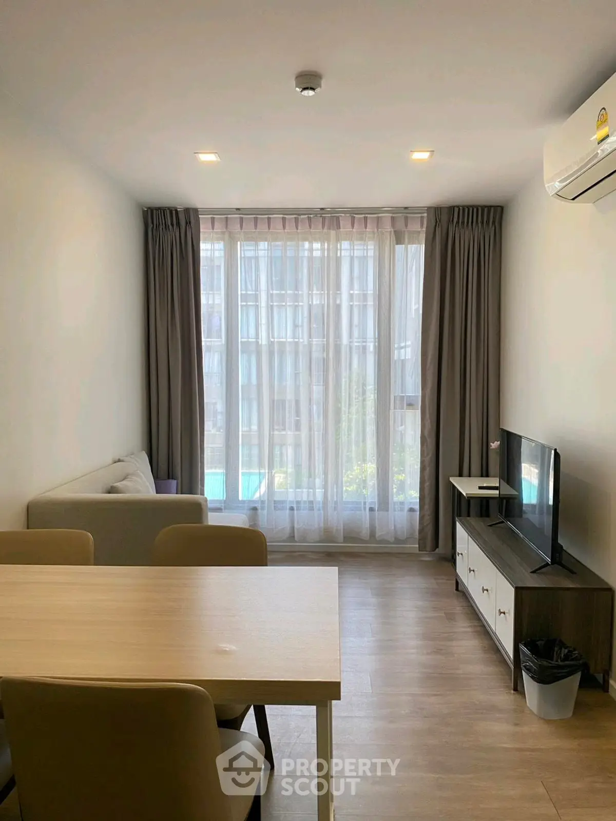 Modern living room with large window, cozy seating, and sleek furniture in a stylish apartment.