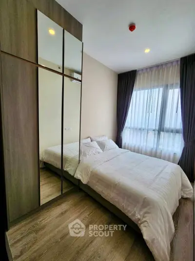 Modern bedroom with mirrored wardrobe and large window for natural light