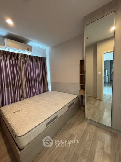 Modern bedroom with large mirror and natural light, featuring a comfortable bed and stylish flooring.