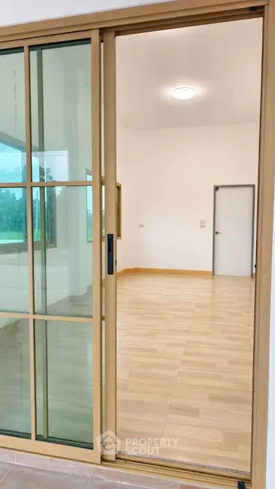 Spacious room with wooden sliding door and large windows, perfect for natural light.