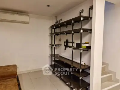 Modern industrial-style living room with custom shelving and air conditioning unit.