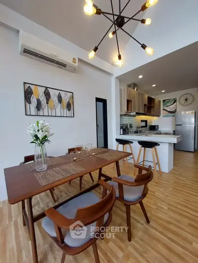 Modern dining area with stylish lighting and open kitchen layout in a contemporary apartment.