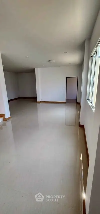 Spacious empty room with large windows and glossy tiled floors