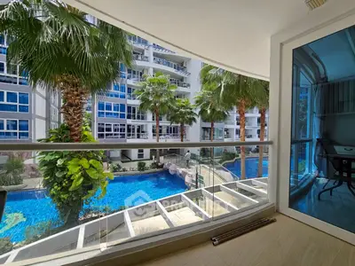 Luxurious balcony view overlooking a stunning pool and palm trees in a modern residential complex.