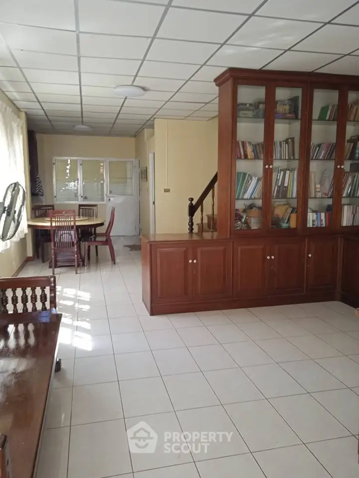 Spacious living area with built-in wooden cabinets and tiled flooring, perfect for a cozy home library.