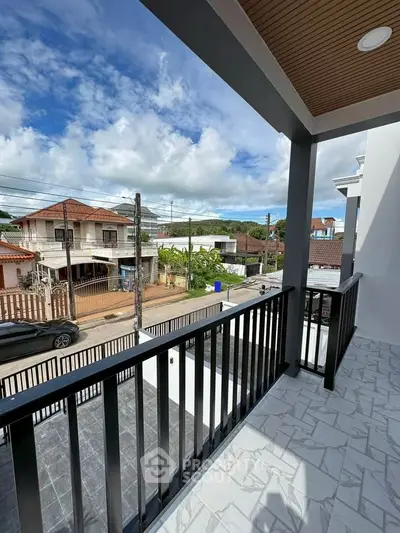 Charming balcony view overlooking a serene neighborhood with clear skies and lush greenery.