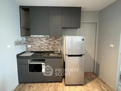 Modern compact kitchen with sleek cabinetry and stainless steel appliances in a stylish apartment.