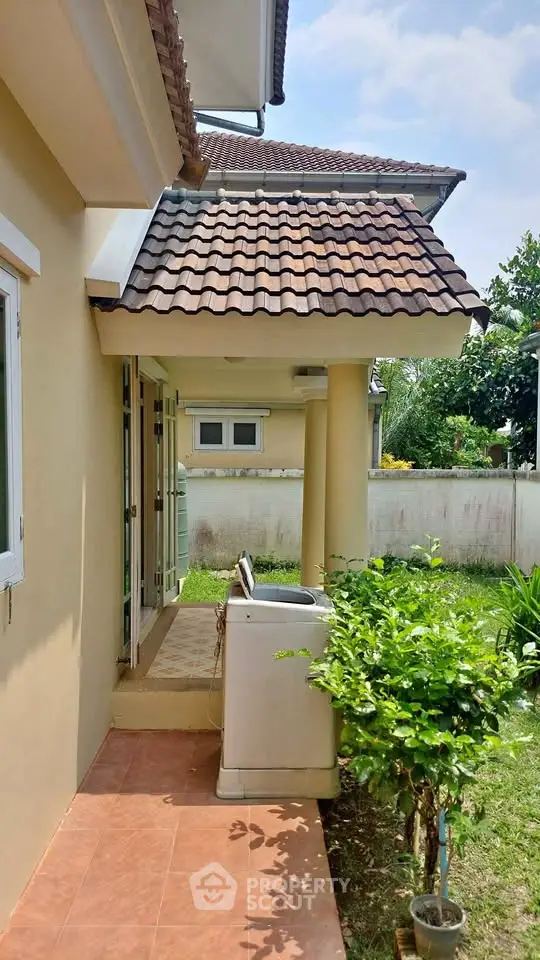 Charming suburban home with tiled roof and lush garden, featuring outdoor laundry area.