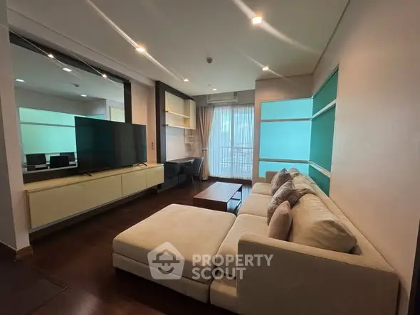 Modern living room with stylish sectional sofa and large TV, featuring elegant built-in shelves and natural light.