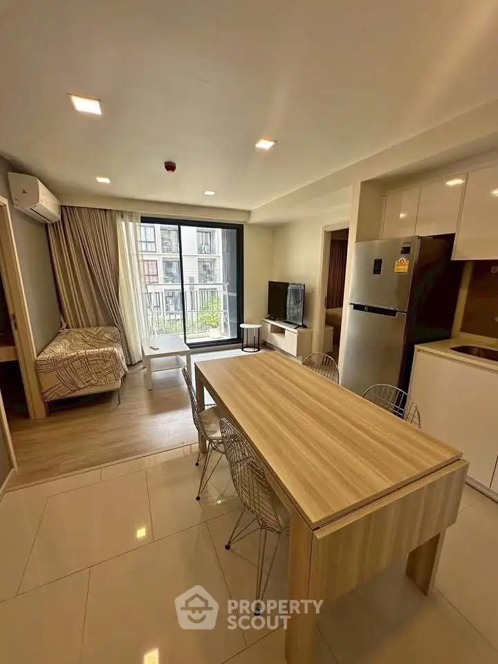 Modern studio apartment with open layout, featuring a cozy living area, dining table, and large windows.