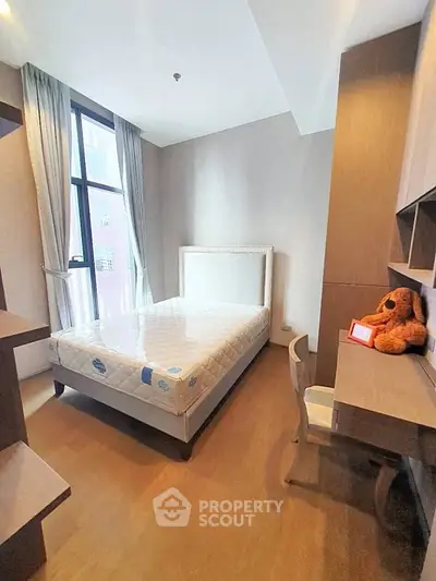 Modern bedroom with large window and cozy workspace, perfect for urban living.