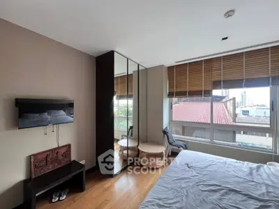 Modern bedroom with large windows and mirrored wardrobe in urban apartment