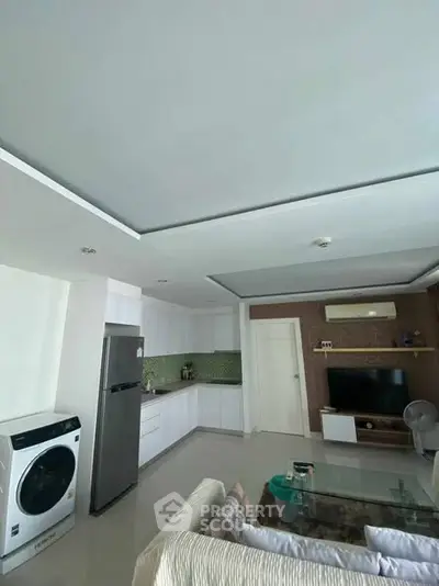 Modern living room with open kitchen, featuring sleek appliances and stylish decor.