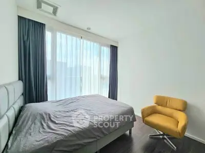 Modern bedroom with large window and stylish armchair, featuring sleek design and natural light.