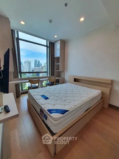 Modern bedroom with city view, featuring a comfortable bed and large window for natural light.