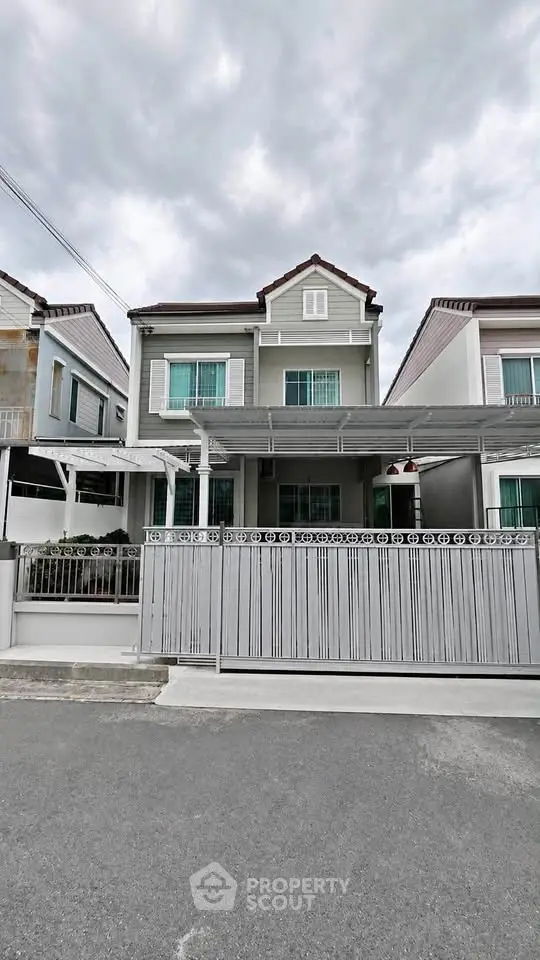 Charming two-story house with modern facade and gated entrance in a serene neighborhood.