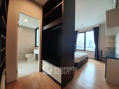 Spacious bedroom with city view, adjacent bathroom, and built-in storage in modern apartment.