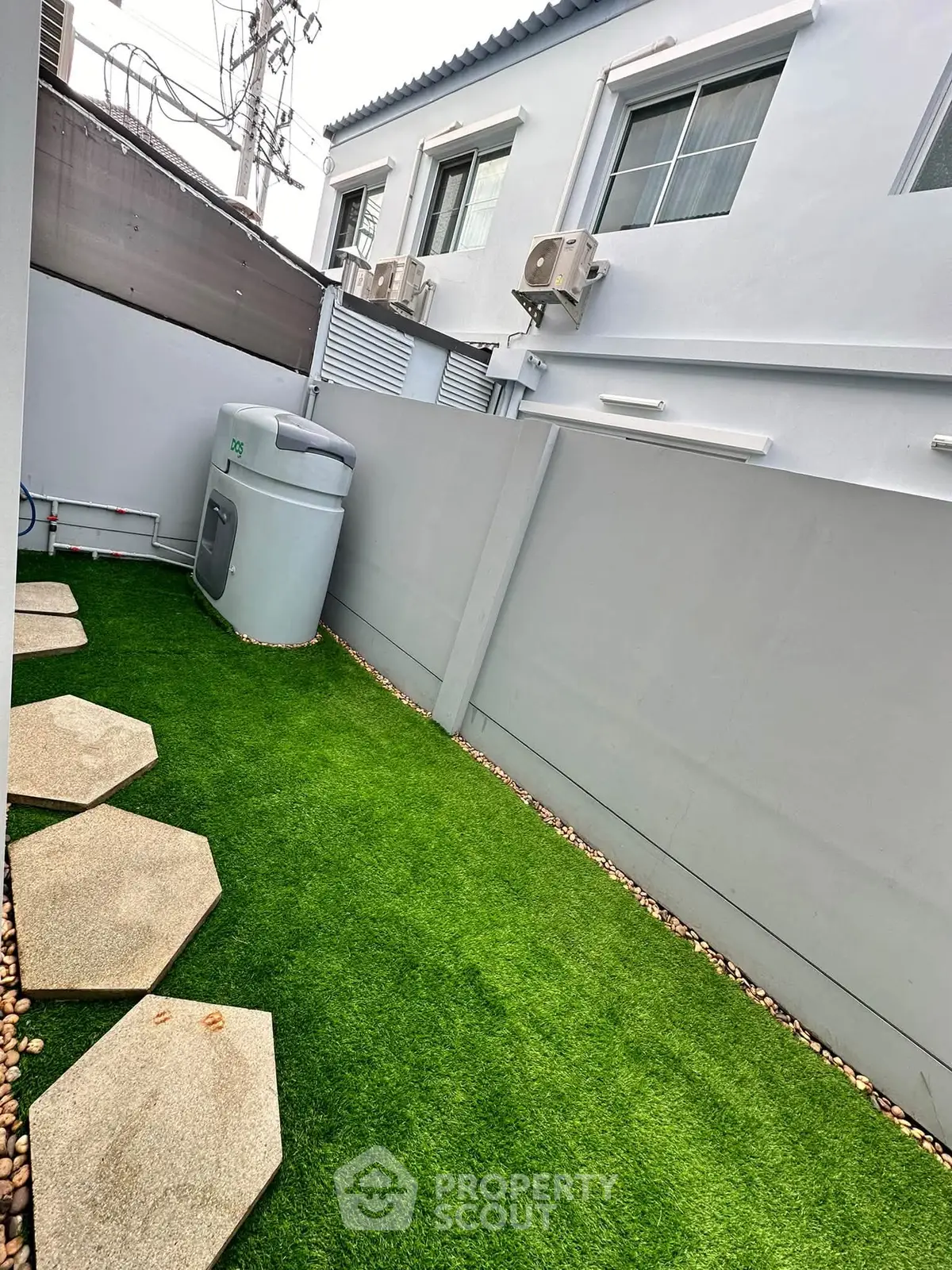 Charming backyard with artificial grass and modern exterior wall design, perfect for outdoor relaxation.