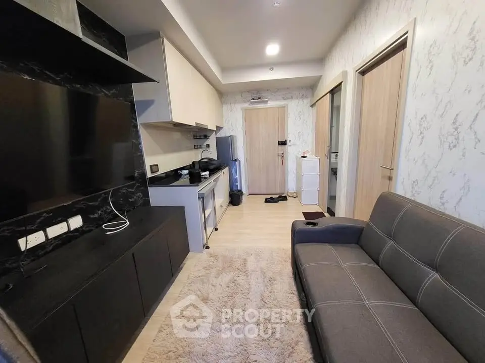 Modern living room with sleek kitchen, cozy sofa, and stylish decor in a compact open-plan layout.