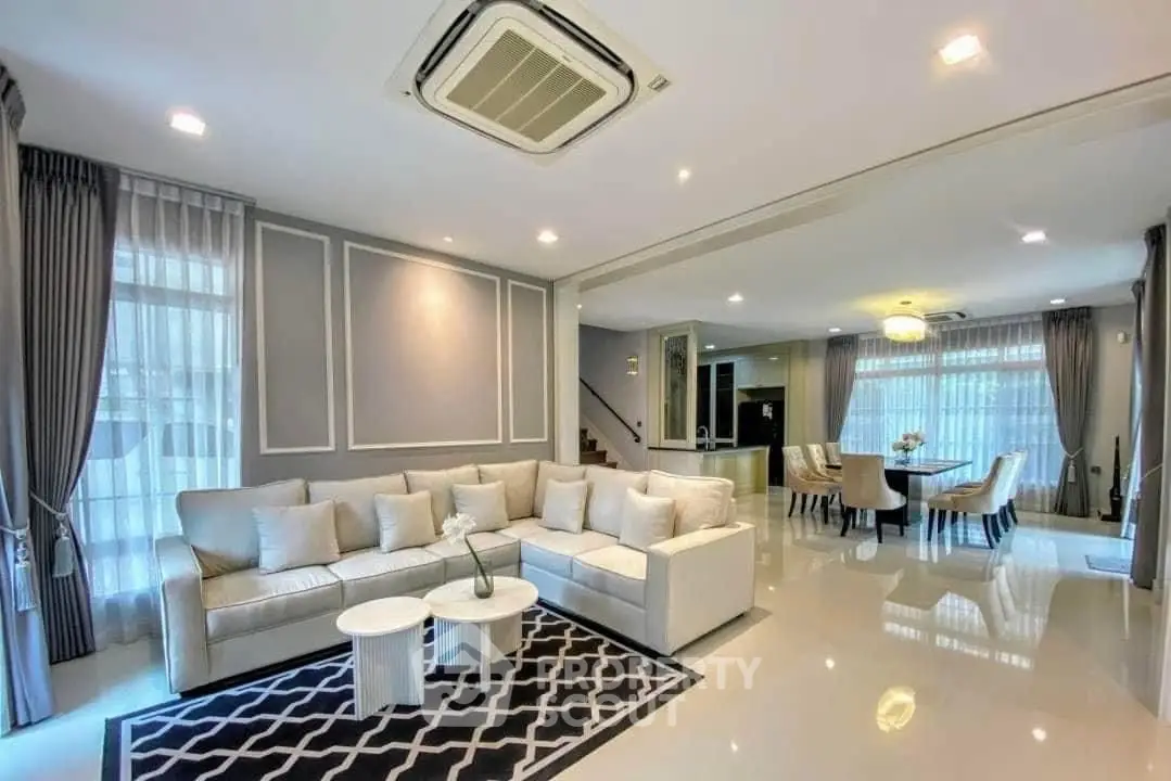 Spacious modern living room with elegant decor and dining area, featuring plush seating and ambient lighting.