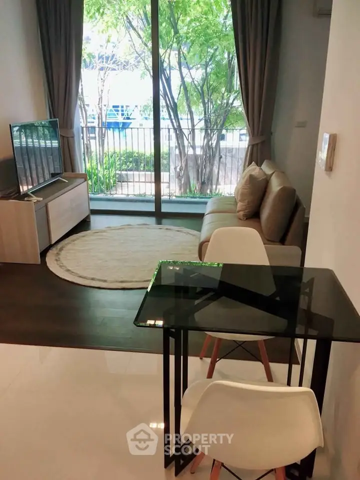 Modern living room with glass table, cozy sofa, and large window view.