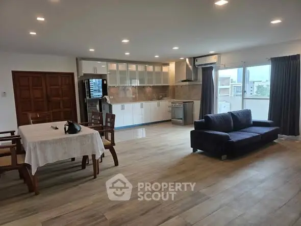 Spacious open-plan living room and kitchen with modern furnishings and ample natural light.