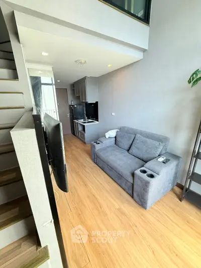 Modern loft-style living room with cozy gray sofa and sleek wooden flooring